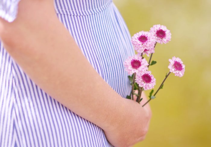 pregnant woman holding petaled flowers